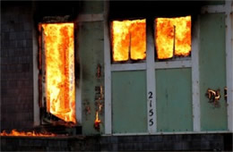 Structure Filled with Fire Inside Seen Through Windows and Door